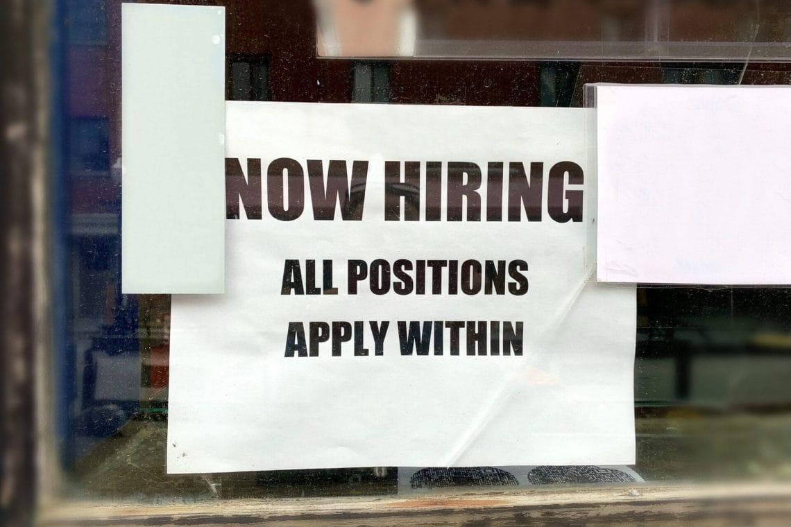 “Now Hiring All positions Apply Within” sign displayed at business’s window mockup friendly for text