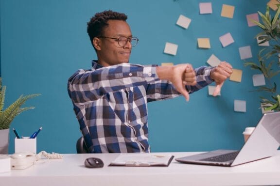 Office employee giving thumbs down in front of laptop screen