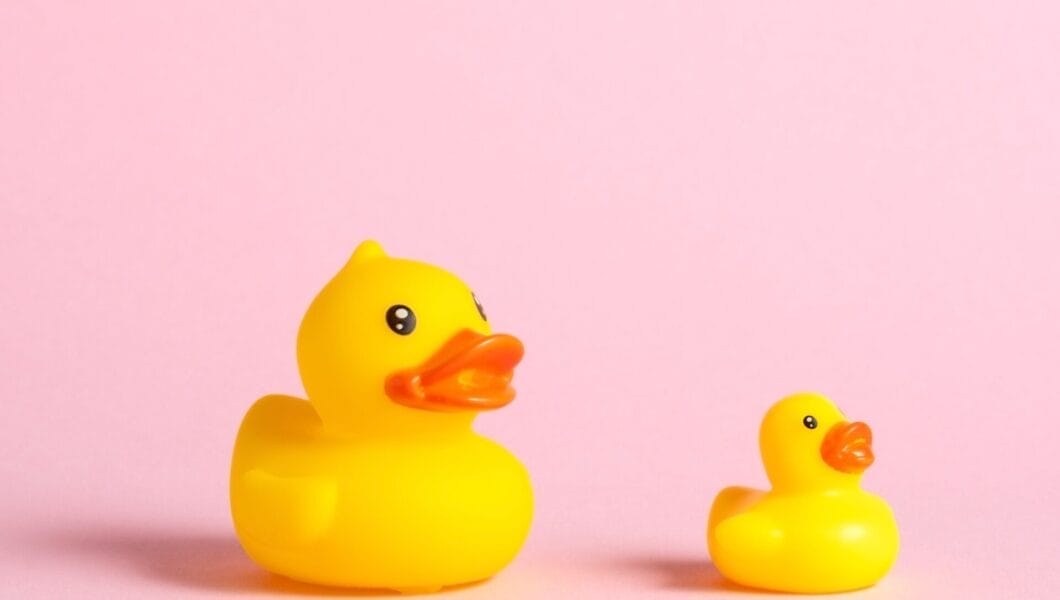 Big and small yellow rubber ducks on pink background