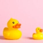 Big and small yellow rubber ducks on pink background
