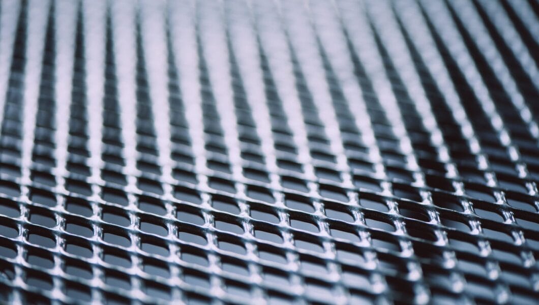 Metal background. Lattice texture with small cells grid. Selective focus point