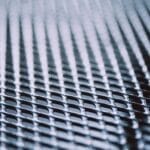 Metal background. Lattice texture with small cells grid. Selective focus point