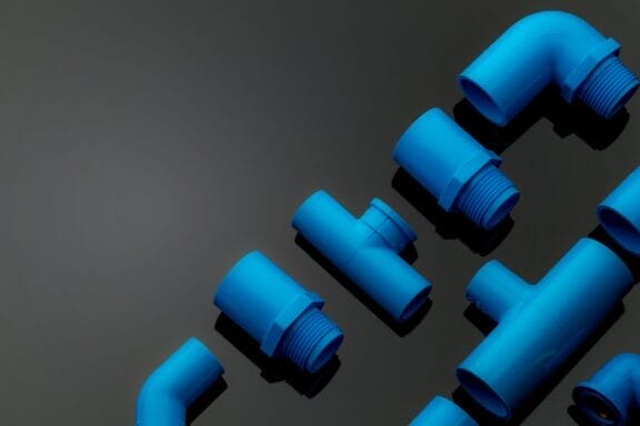 Set of blue PVC pipe fittings isolated on dark background. Blue plastic water pipe. PVC accessories
